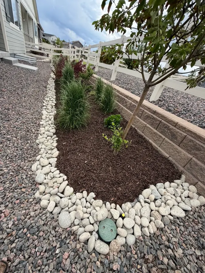 Rock border landscaping with mulch bed and retaining wall