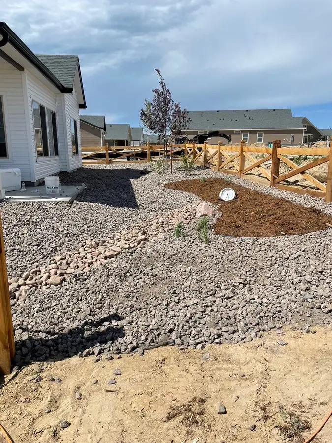 Backyard gravel and mulch landscaping with tree planting