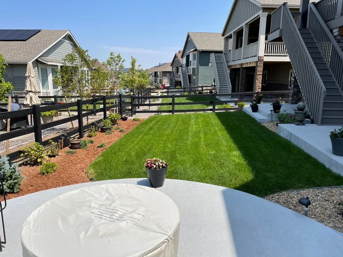 Lush green sod backyard with patio and garden beds