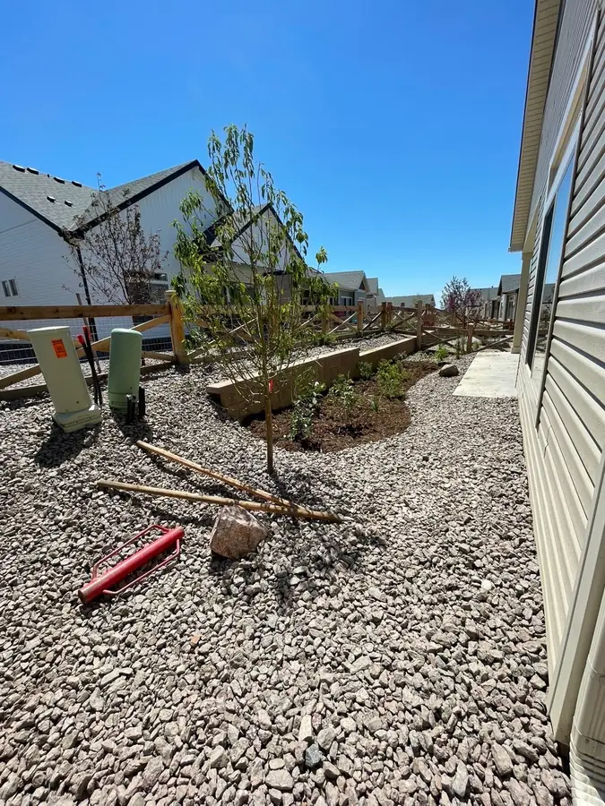 Side yard gravel xeriscape with trees and planting beds
